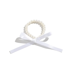 Detailopname van de elegante witte satijnen strik en parelketting op wit oppervlak