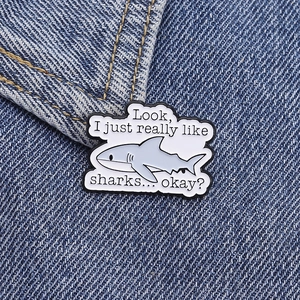 Detail of funny shark quote enamel pin on denim fabric with vibrant colors