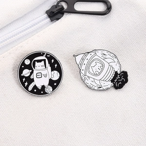 Detail of space cat enamel pins on white canvas bag showing astronaut cat and rocket motifs