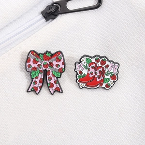 Detail of cute strawberry bow and red cowboy boot enamel pins on white canvas bag