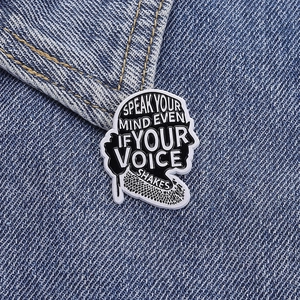 Détail du pin's émaillé avec citation sur le tissu d'une veste en jean bleu