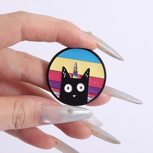 Detail showing the colorful enamel unicorn black cat brooch held by hand for scale