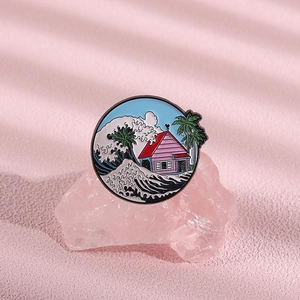 Detail of round enamel brooch featuring coastal scenery with waves and palm tree motifs