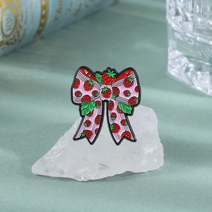 Detail of cute strawberry bow enamel pin on white stone with soft background
