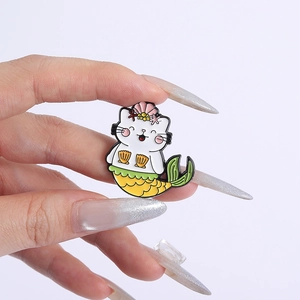 Détail d'un pin's en émail chat sirène mignon avec coquillage rose et queue jaune