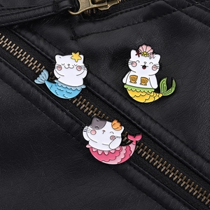 Three colorful cat mermaid enamel pins pinned on a black leather jacket pocket