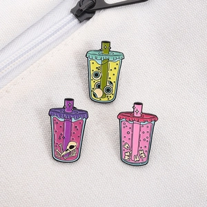 Detail of gothic enamel pins showing beverage cups with eyeballs and bird skull on white canvas