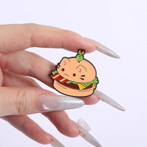 Detailed view of creative cartoon cat burger enamel pin badge on hand for scale