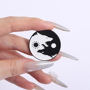 Detailed view of yin yang wolf enamel pin with sun and moon icons held by hand