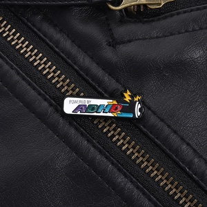 Detail showing 'Powered by ADHD' enamel pin attached to a black leather jacket zipper