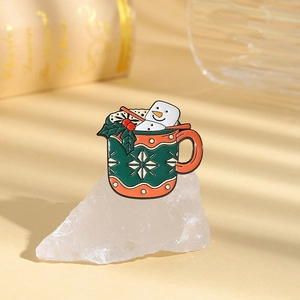 Detail of green enamel Christmas mug brooch with snowman on crystal stone background