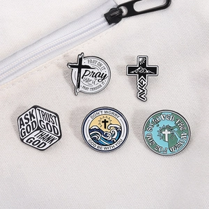 Close-up of five religious enamel pins with cross and mountain designs on canvas