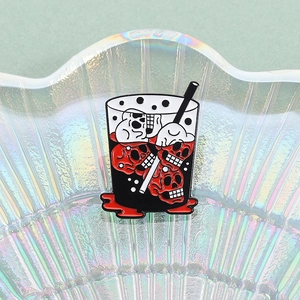 Macro shot of dark punk skull drink enamel pin displayed on a shell-shaped iridescent tray