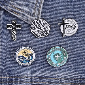 Detail view of five assorted religious enamel pins on a dark blue denim background