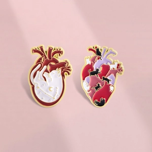 Vue détaillée de deux broches cœur anatomique avec motifs de chats et de galaxie