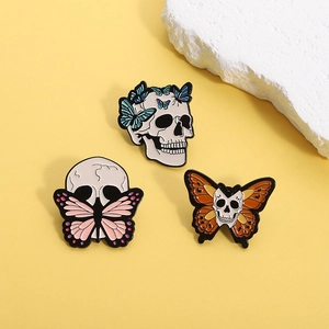 Gothic skull and butterfly enamel pin set in blue, pink, and orange on yellow background