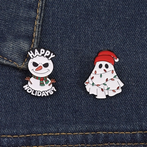 Detail showing a funny enamel snowman and ghost brooch on blue denim fabric background
