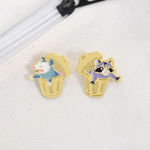 Close-up of enamel raccoon and opossum pins on white canvas bag with detailed metal texture