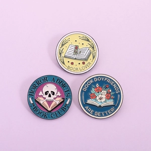 Three enamel pins featuring book lover motifs and horror book club text on purple background