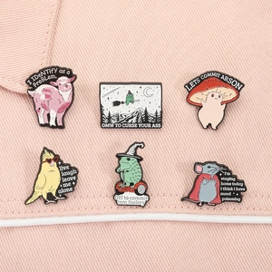 Set of six funny animal and mushroom enamel pins displayed on pink denim background