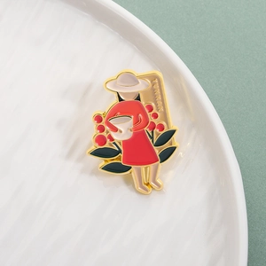 Detail einer Emaille-Brosche eines Mädchens in Rot mit YUNNAN-Schriftzug auf Weiß