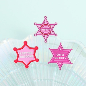 Gros plan sur des badges d'étoile rose avec textes Sheriff et Cutie on Duty