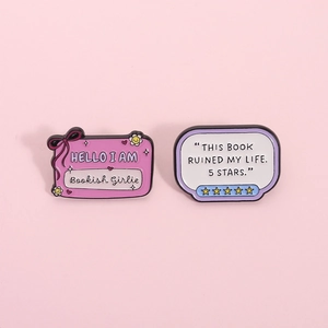 Detail view of pink and white enamel badges featuring humorous bookish girlie quotes