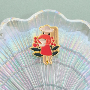 Detail einer Emaille-Brosche mit einer Frau im roten Kleid und goldener YUNNAN Aufschrift