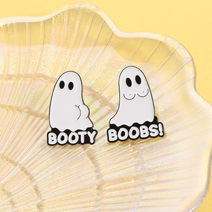 Détail de pins fantômes humoristiques avec texte booty et boobs sur plateau nacré
