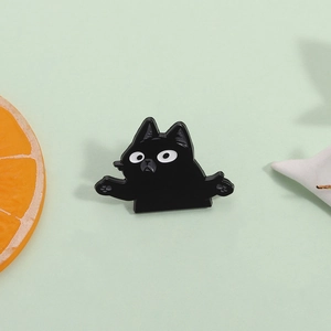 Broche chat noir en émail avec grands yeux et détails de pattes sur fond vert doux