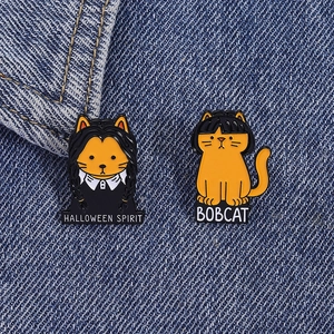 Detailed view of Halloween cat enamel pins on denim, featuring Wednesday Addams style feline