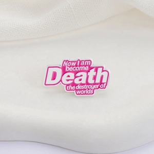 Pink enamel pin featuring Oppenheimer quote Now I am become Death on white stand