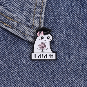 Cute ghost graduation enamel pin with I did it banner and black mortarboard on denim