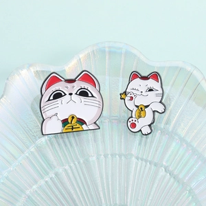 Detail of cartoon lucky cat enamel pins with gold bells and colorful dripping oil craft