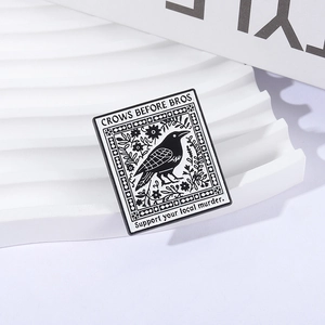 Detailed close-up of Crows Before Bros enamel pin with floral patterns on white stand
