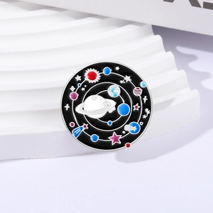 Détail d'un pin's émaillé univers avec planètes et étoiles sur fond de texture blanche