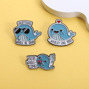 Detailed view of three cartoon whale enamel pins with funny puns on a bright yellow background