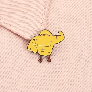 Détail macro du pin's émaillé poussin musclé sur une texture de tissu rose