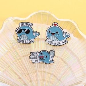 Three cute blue whale enamel pins with funny ocean puns on an iridescent shell display