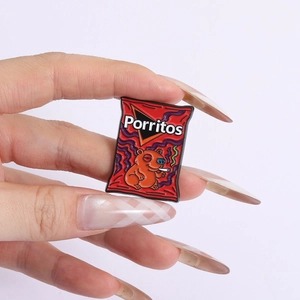 Detail of funny red snack bag enamel pin featuring a smoking capybara and cartoon graphics