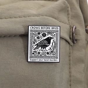 Funny crow enamel brooch with Crows Before Bros text on olive green fabric background