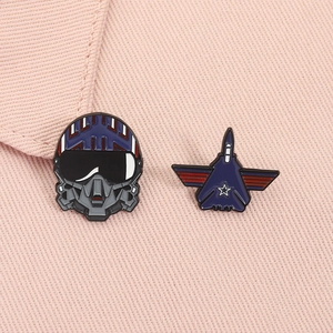 Detailed set of pilot helmet and fighter jet enamel pins on pink fabric background