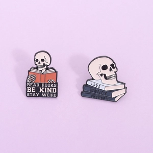 Enamel skull and book pins with text Read Books Be Kind Stay Weird in vintage style