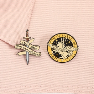 Macro shot of mythological Percy Jackson pins featuring Pegasus and sword detail on fabric