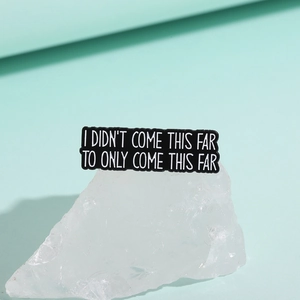 Close-up of black enamel brooch with white I DIDN'T COME THIS FAR TO ONLY COME THIS FAR quote