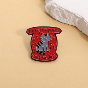Broche en émail rouge motif chat gris avec texte The horrors persist but so do i