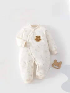 Détail d'une barboteuse en coton fleuri avec patch ours en peluche et boutons pression