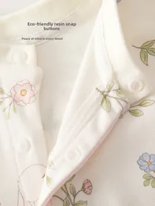 Détail de l'encolure d'un barboteuse bébé à fleurs avec pressions en résine