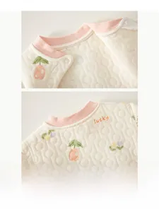 Detailed view of quilted cotton baby pajamas with cherry pattern and pink trimmed neckline