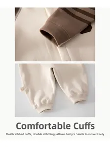 Détails des poignets côtelés et des coutures renforcées d'une grenouillère bébé en beige